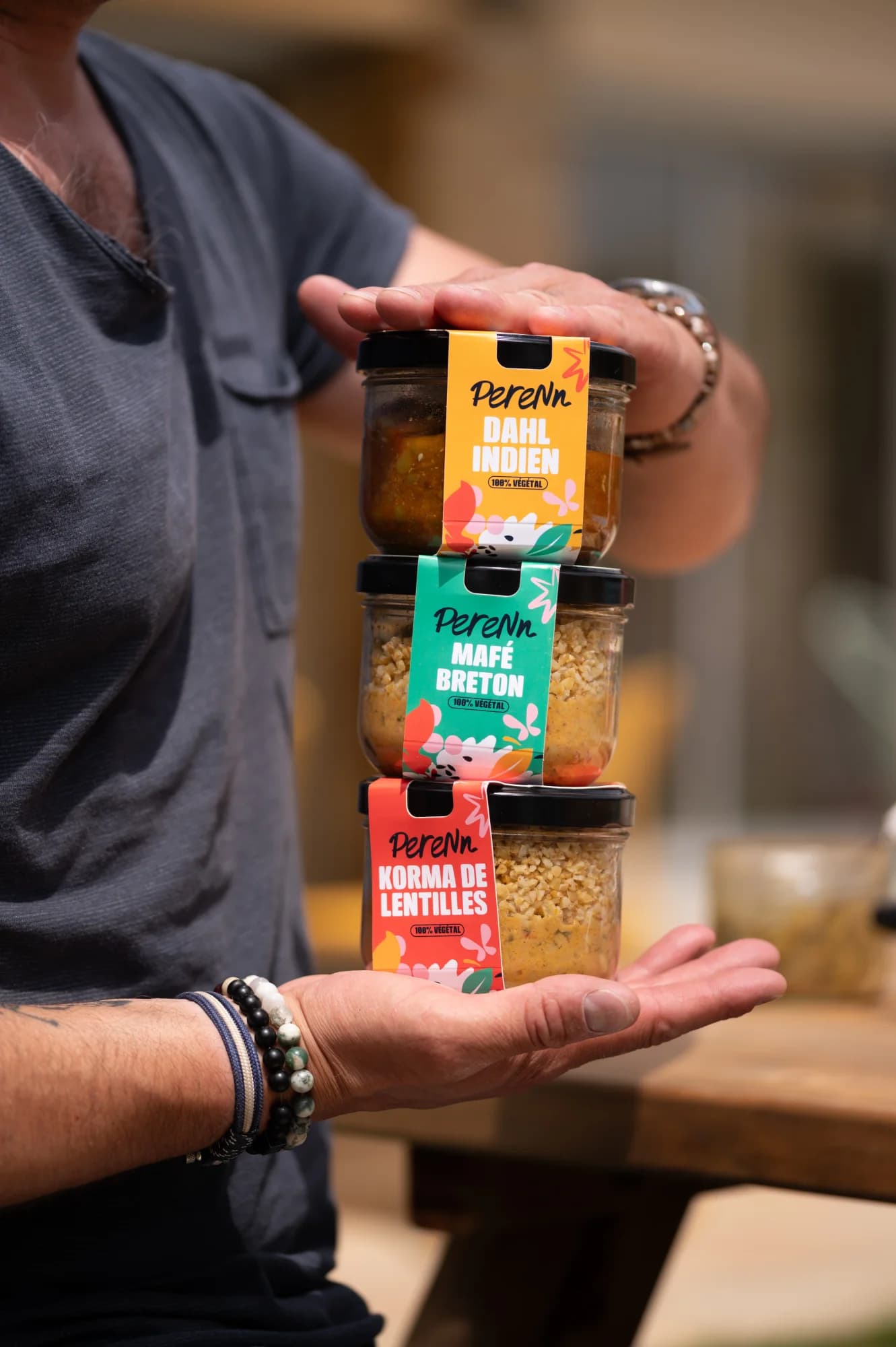 Des mains tenant trois bocaux PERENN : Dahl indien, Mafé breton, Korma de lentilles